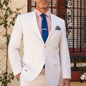 White suit with pink button-up and navy tie