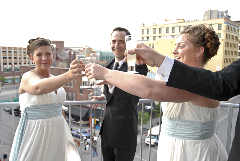 Minneapolis couple clinks glasses with wedding party on a rooftop