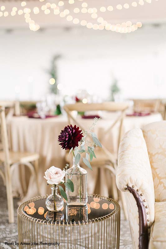 Simple white and maroon flowers in glass vases on tabletops