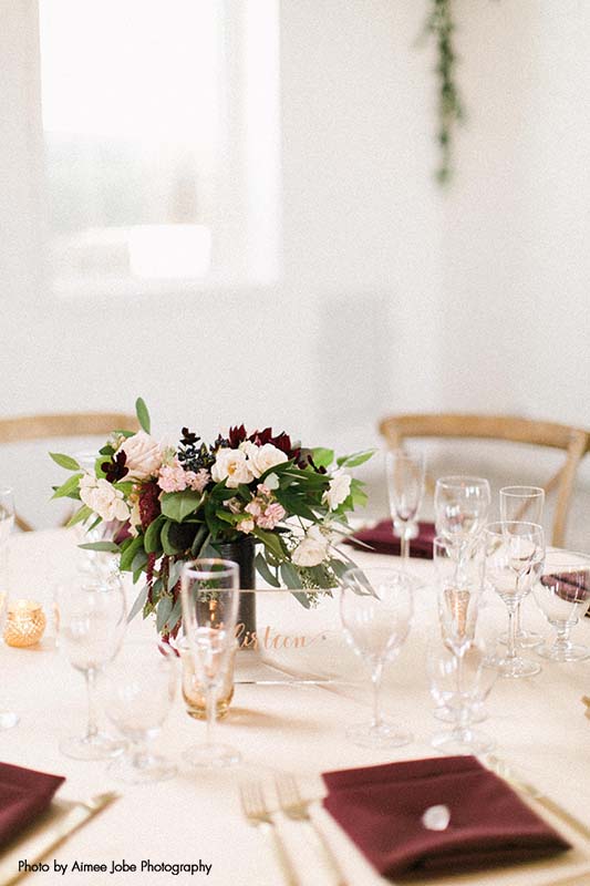 Modern wedding table seating with white and maroon accents