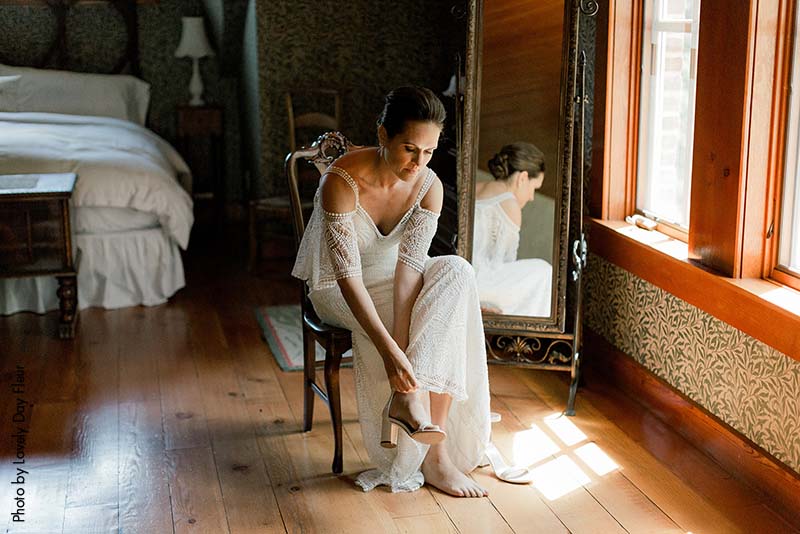 Bride in boho gown putting on her shoes before the ceremony