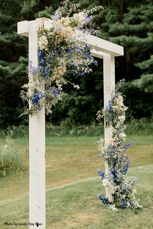 Wedding ceremony arch wrapped with wild flowers