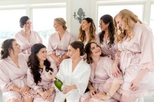 Bridesmaids get ready in pink robes with bride in white robe