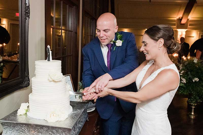 Groom in blue suit bride in white dress cut wedding cake