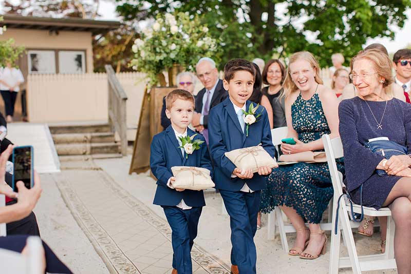 Ring bearers in dark blue suits, walking down the aisle