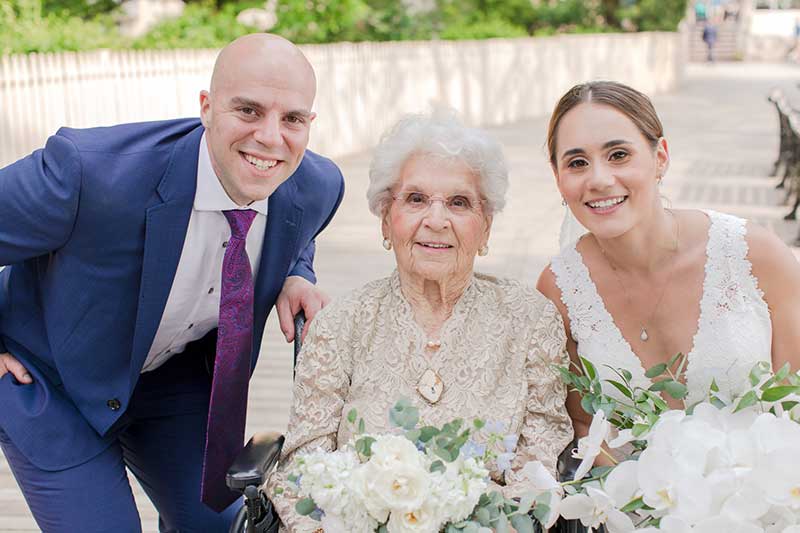 Bride in white dress groom in blue suit with grandmother