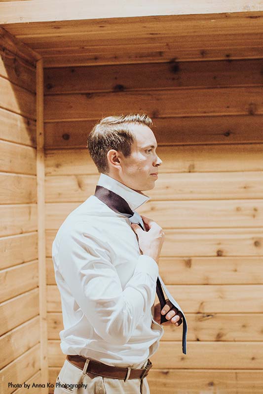 Grooms puts on tie before elegant Minnesota wedding
