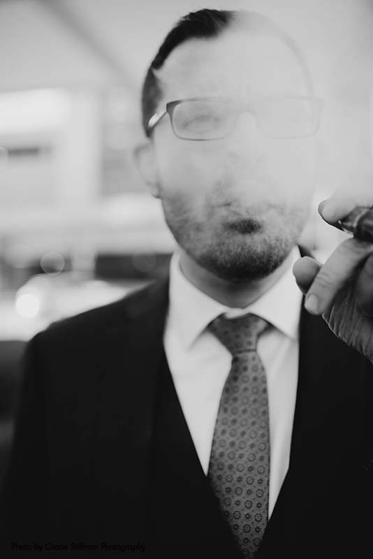 Groom smokes cigar after wedding