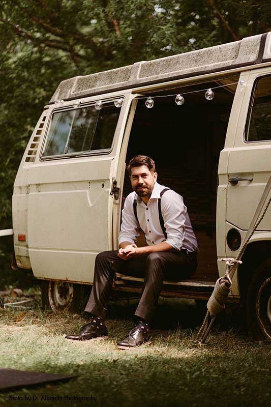 Groom sits in vintage van before wedding