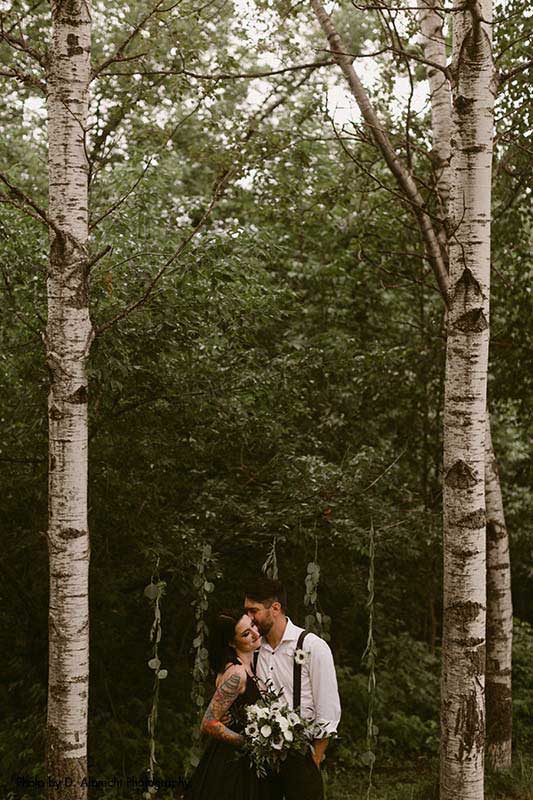 Couple poses in forest with birch trees