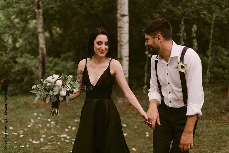Bride in black wedding dress and groom in suspenders at outdoor wedding