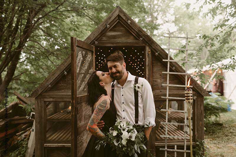 Bride and groom with rustic shed at wedding