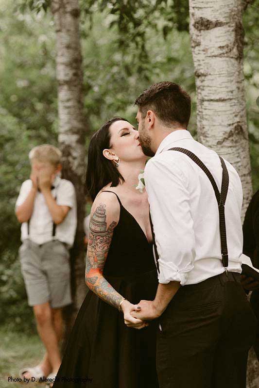 Bride and groom share first kiss at outdoor backyard wedding