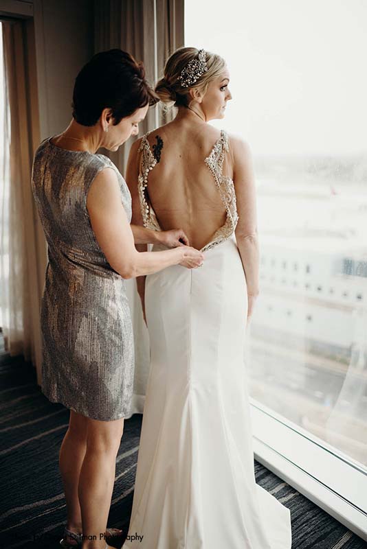 Mother of the bride zips up bridal gown