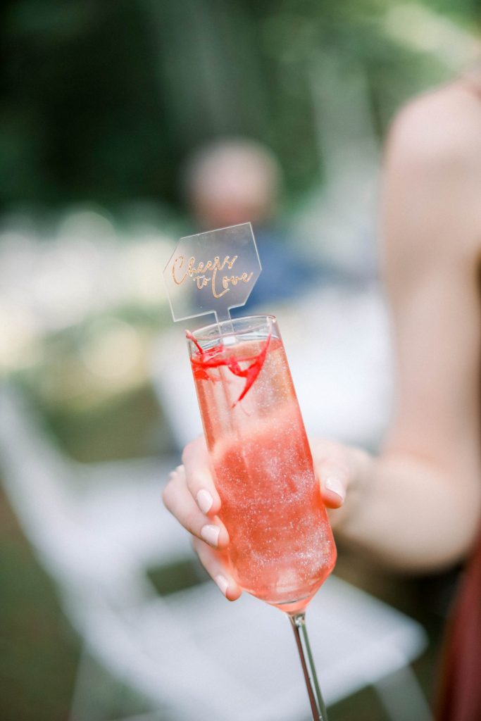 Pink signature drink at wedding with "Cheers to Love" sign in it