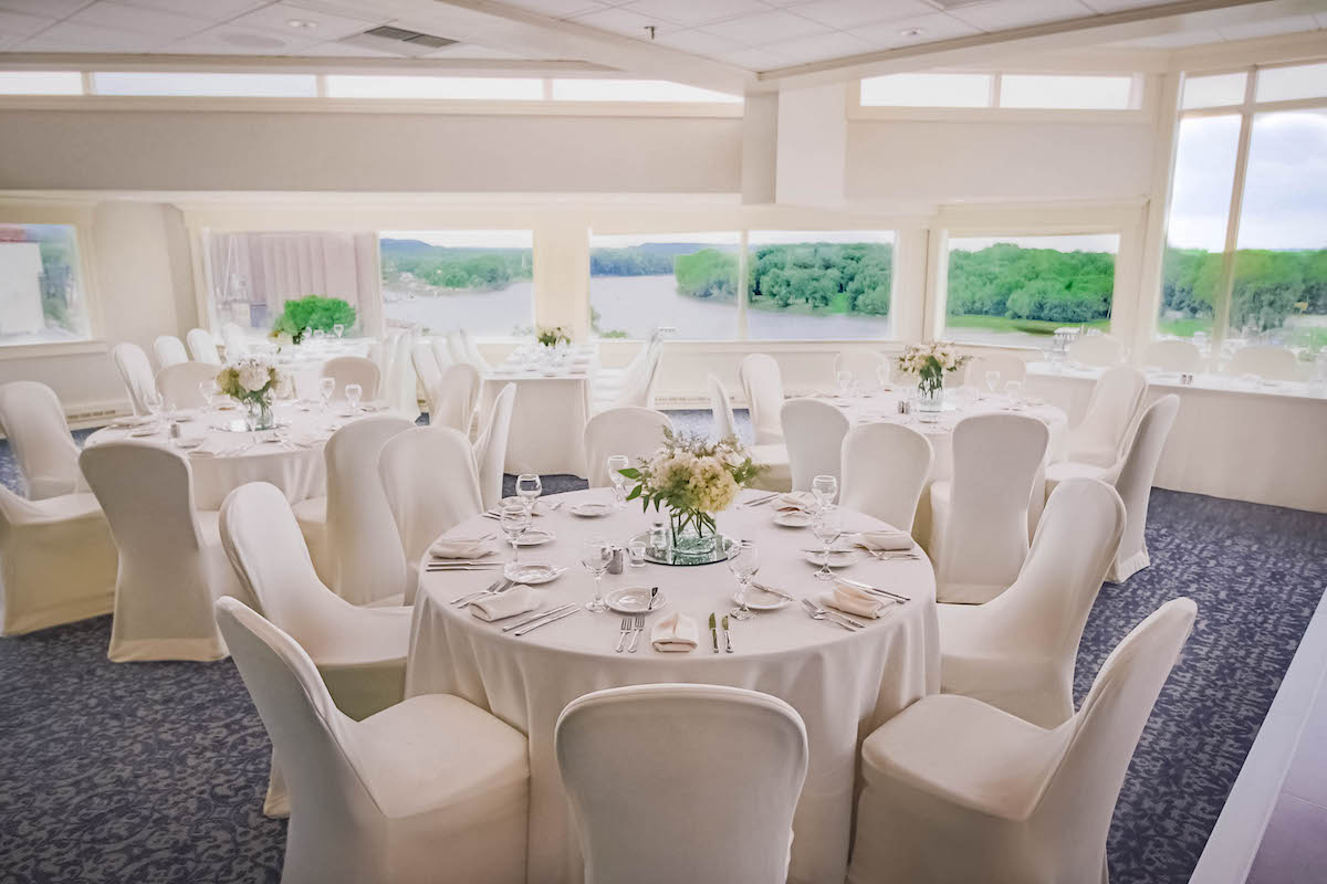 Hotel wedding reception room with white chairs and tables overlooking a river