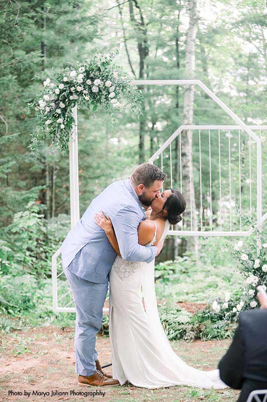 Bride and groom share first kiss at outdoor wedding