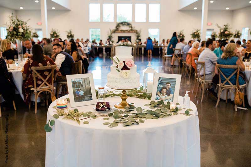 Modern wedding cake table with cake and photos of couple
