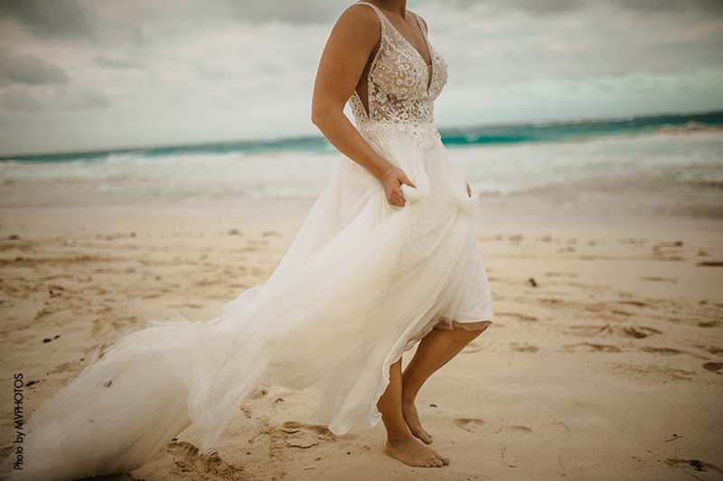 Bride walks along beach in bridal gown