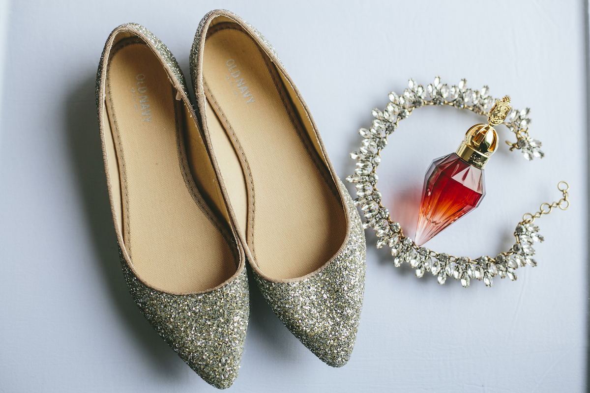 Silver glitter bridal flats lay next to vintage perfume bottle