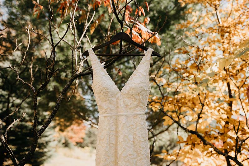 Sleek and detailed bridal gown hangs from tree