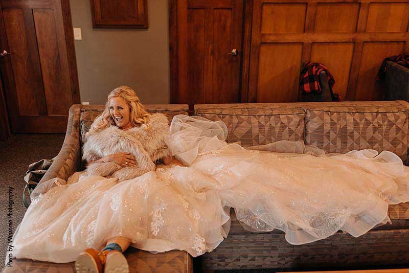 Bride sits on couch with dress laid out