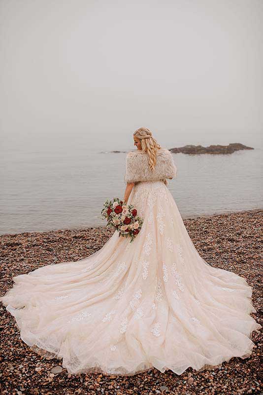 Bride stands on beach in sequin tulle ballgown