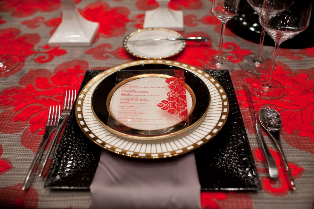 Placesetting with square crocodile chargers, gray napkin, and acrylic red printed menus