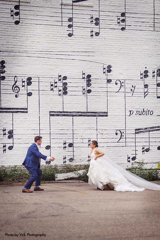 Bride running towards groom in front of music sheet wall