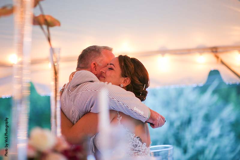 Bride and father hug at backyard wedding reception