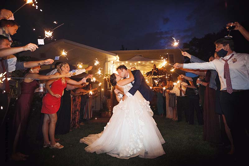 Bride and groom kissing under sparkler send off