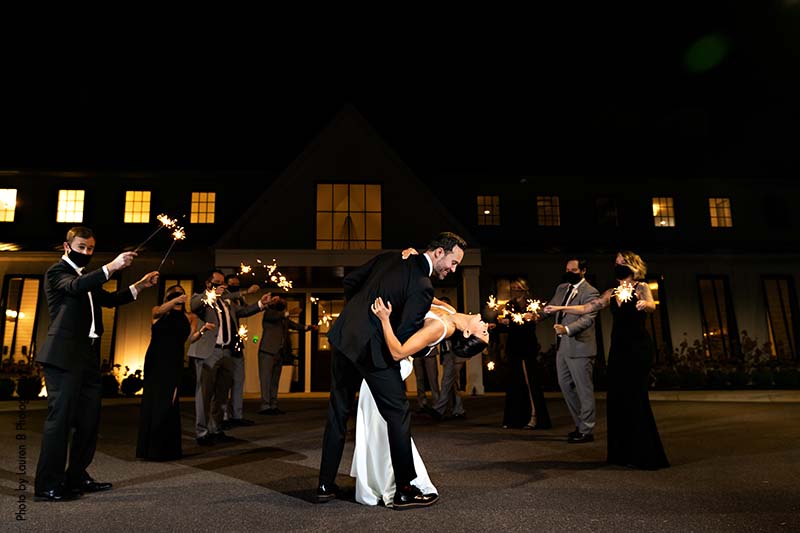 Bride and groom walk out of wedding under sparklers