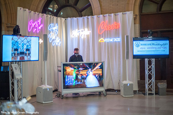 DJ performs at wedding with neon signs in background