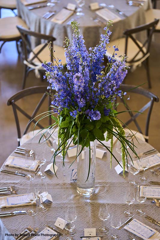 Tall wedding centerpiece with purple flowers and greenery