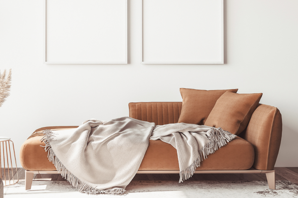 Rust-colored couch with a neutral-toned blanket on top 