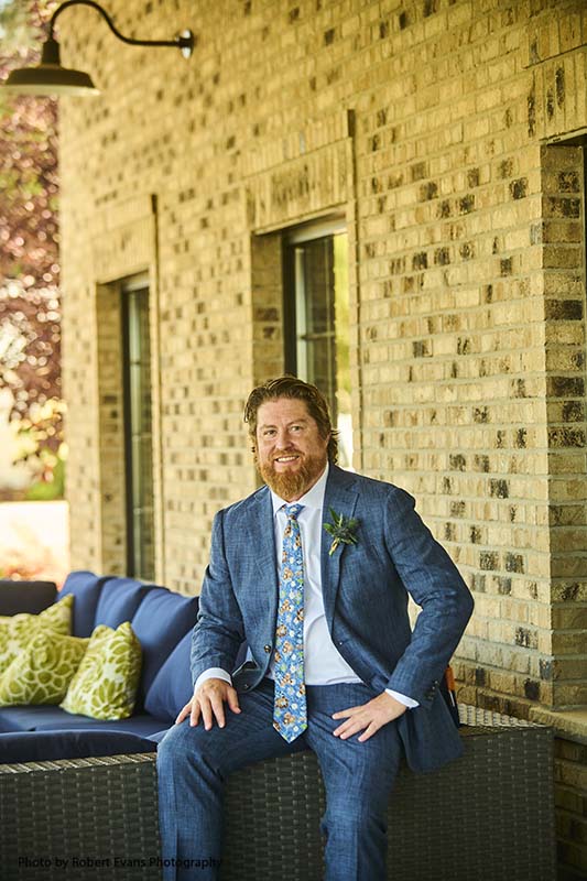 Groom poses in navy tuxedo and floral tie