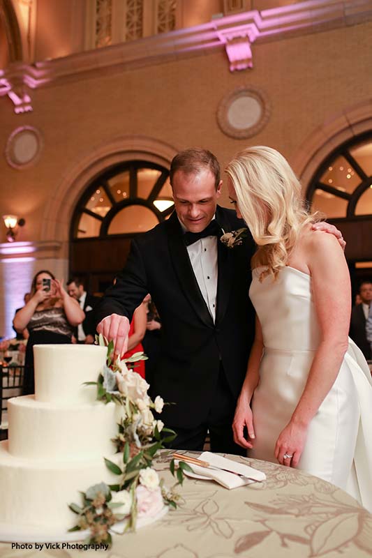 Bride and groom cutting cake at ballroom reception
