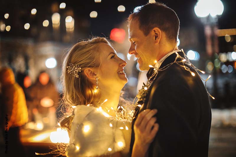 Bride and groom posing with string lights wrapped around them