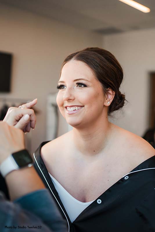 Bride getting makeup done before wedding ceremony