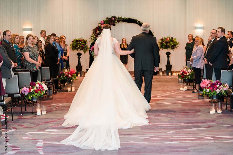 Father walks bride down aisle at ballroom wedding