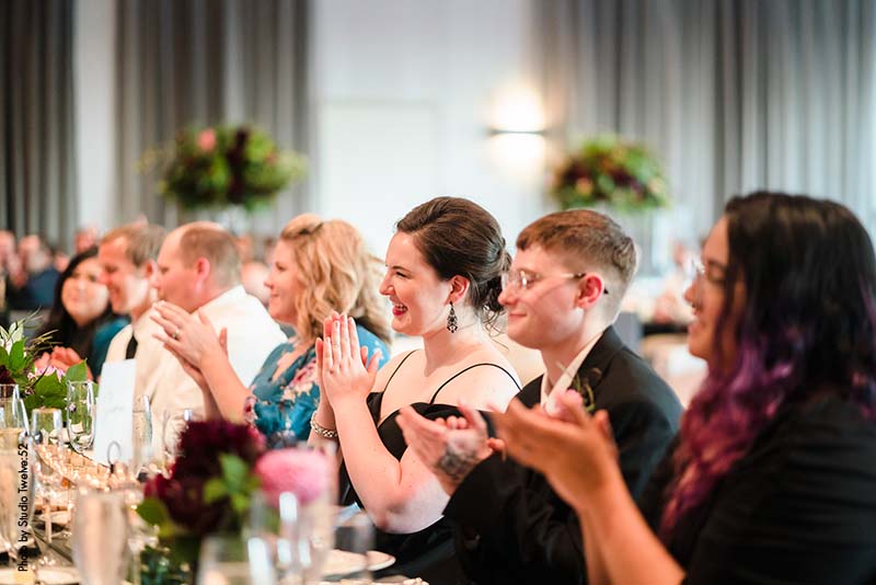 Wedding guests clapping for speech at reception