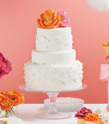 3-tier white wedding cake with an orange and pink flower on top