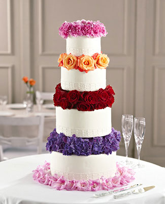 Tall 4-tier wedding cake with layers of multi-colored flowers between each tier