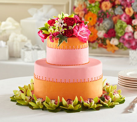 Orange and pink wedding cake with flowers on top