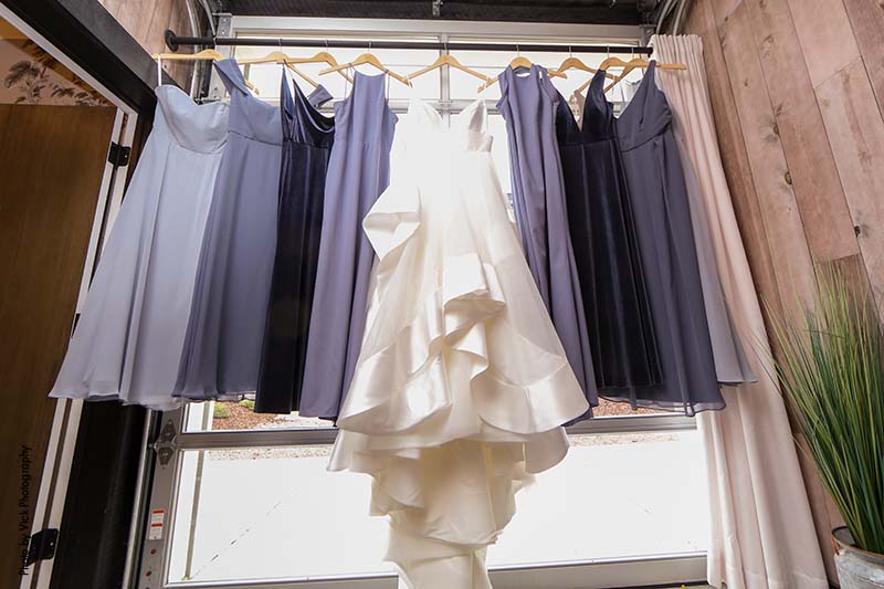 Bridal gown and bridesmaid dresses hanging before ceremony