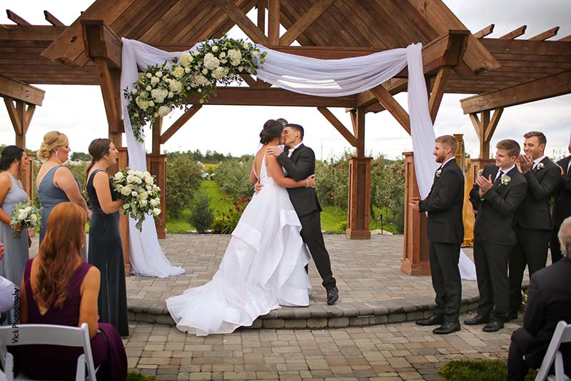 Bride and groom share first kissing at outdoor wedding ceremony