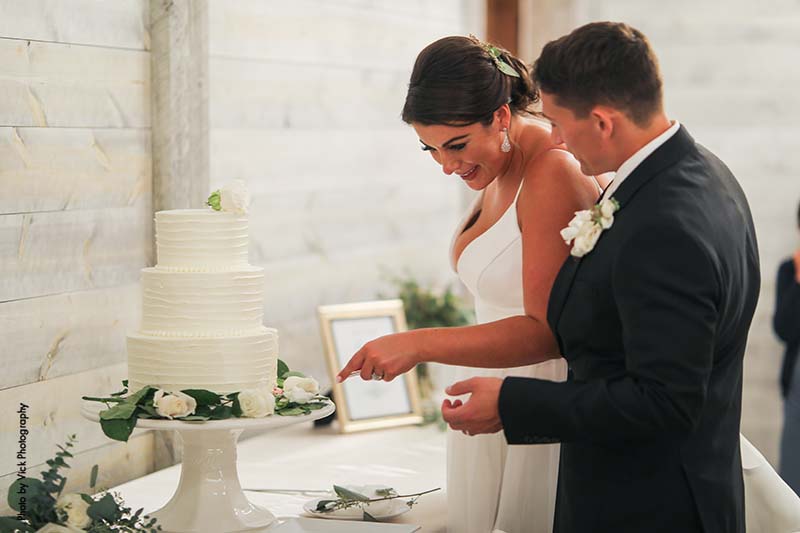 Bride and groom cutting cake at barn reception