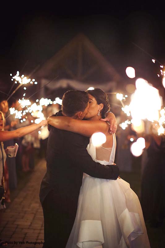 Bride and groom share a kiss under a sparkler send off