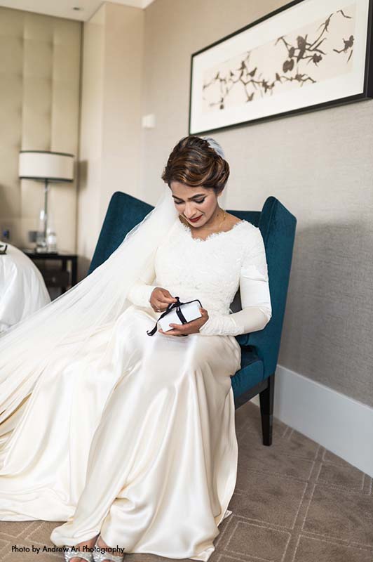 Bride sits in navy chair and opens a gift