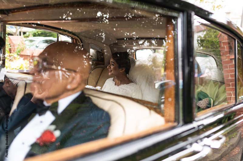 Bride sits in back seat of a vintage car before wedding